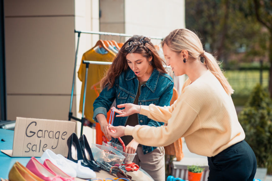 Two women looking at jewelry at a garage sale.
