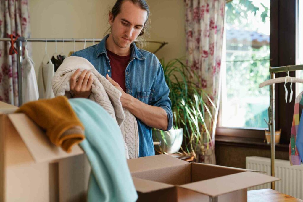 Man preparing to pack sweater into a box.