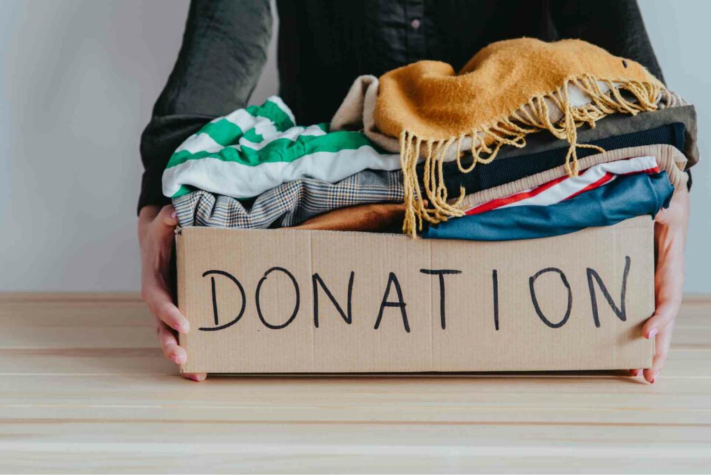 Person setting down a box of clothing marked for donation.