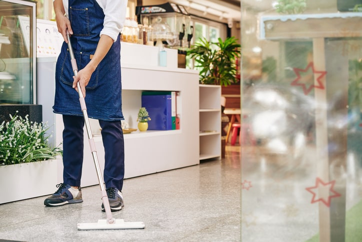 Person cleaning the floor of a retail store or restaurant.