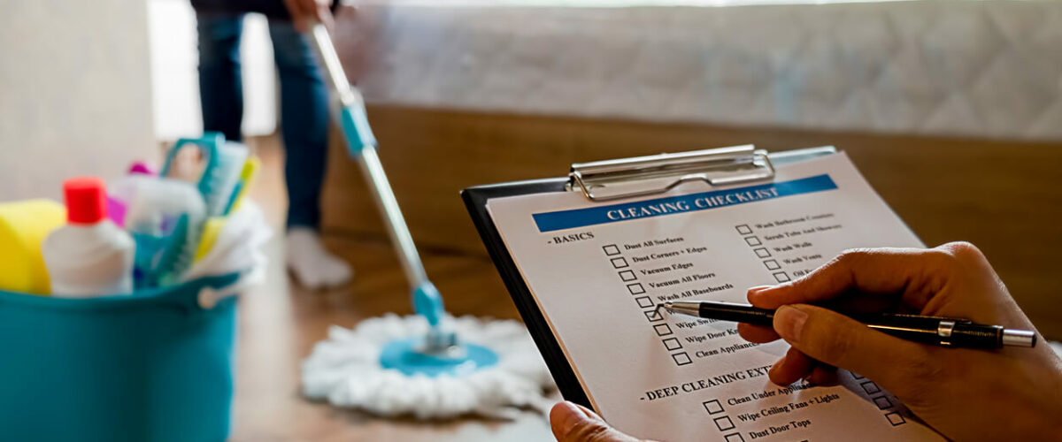 Person checking off a cleaning checklist while another person mops.