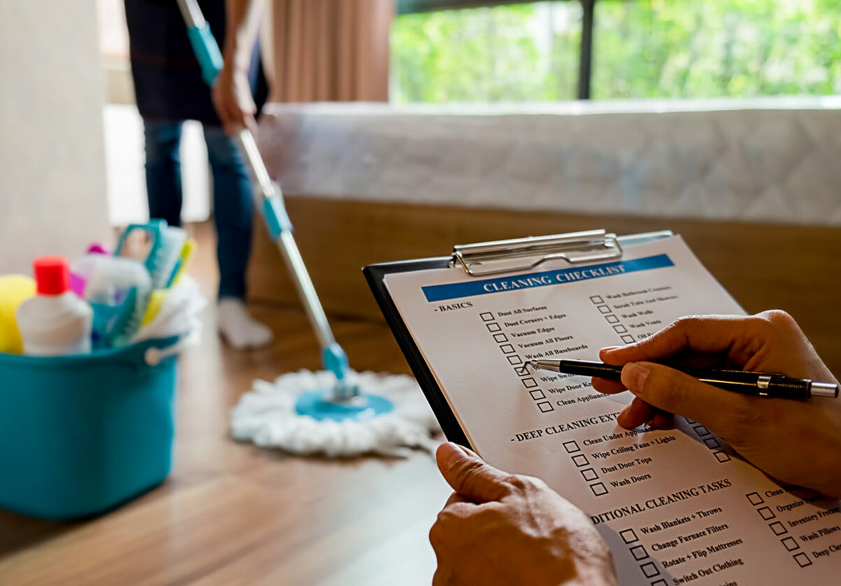 Person checking off a cleaning checklist while another person mops.