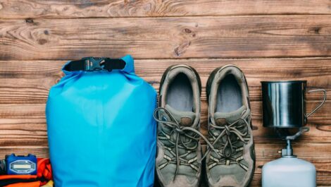 Tent, headlamp, boots, and other camping gear sitting on a wooden table.