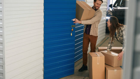 Couple smiles while moving boxes into a storage unit.