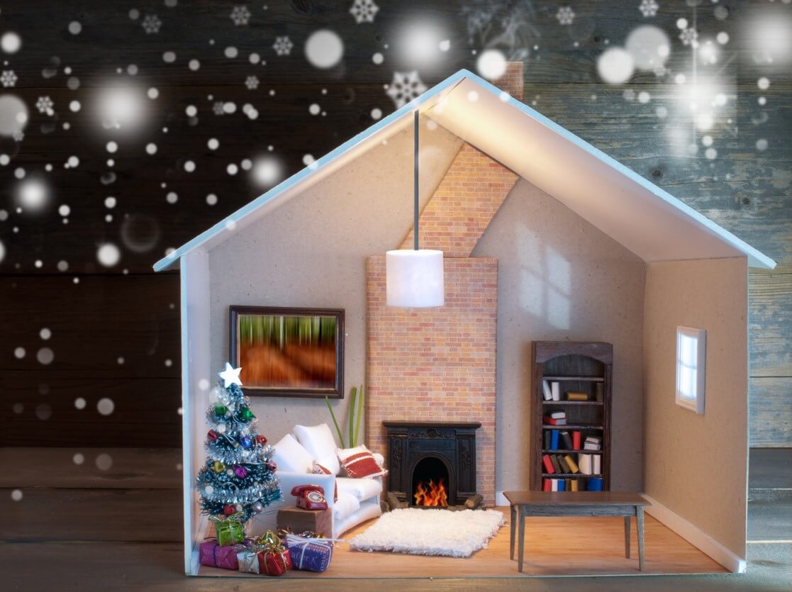 Model home on a wooden table with snowflakes falling from above.