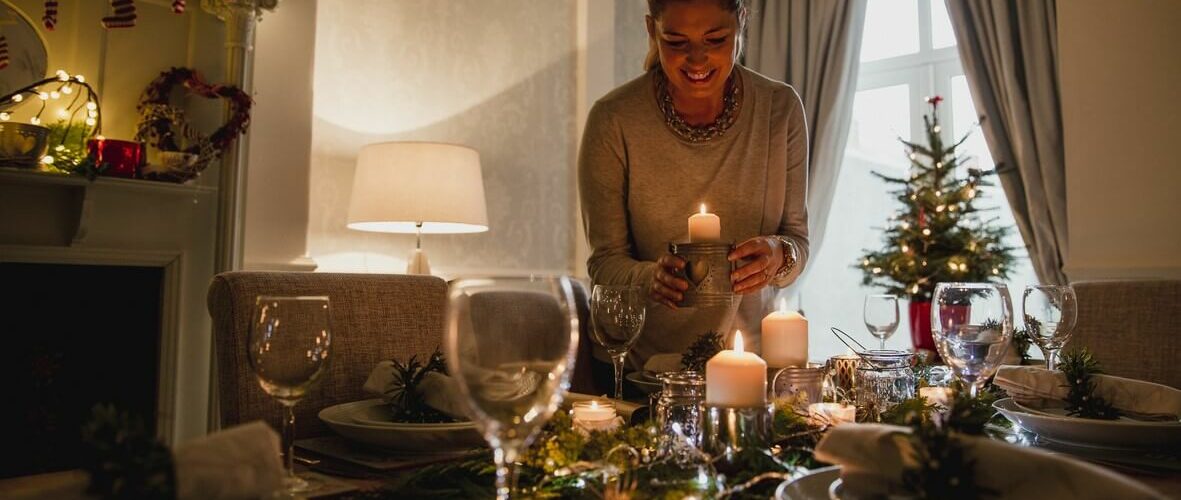 A woman decorating the table with candles for a holiday dinner.