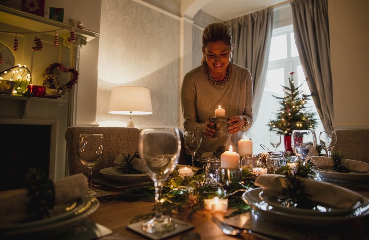A woman decorating the table with candles for a holiday dinner.